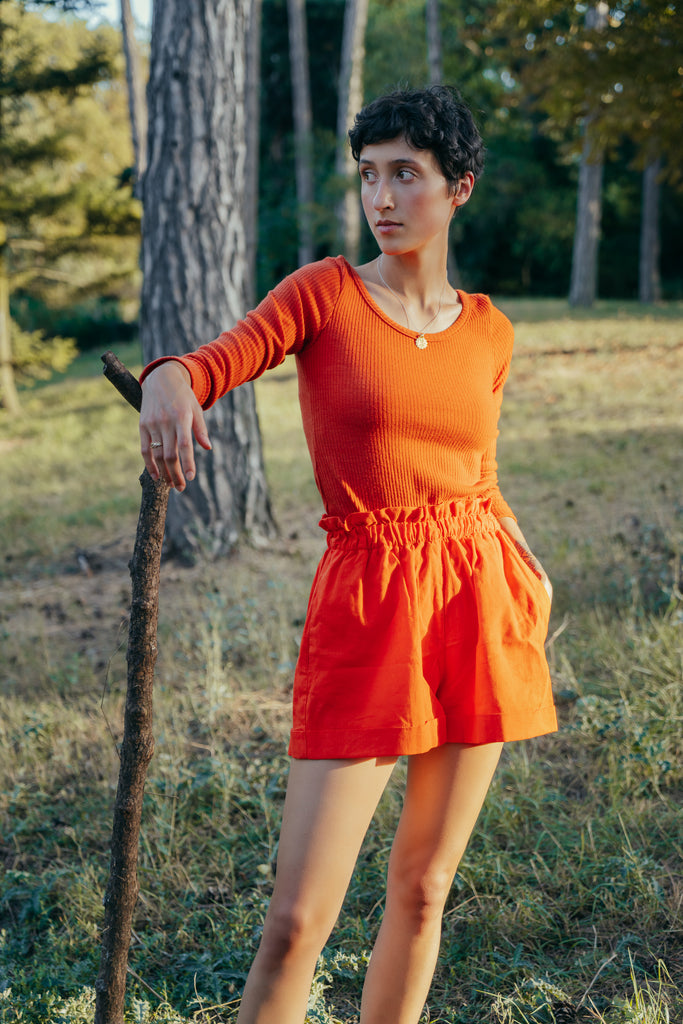 Angele is wearing our tangerine set, made of deadstock fabrics while posing at the forest